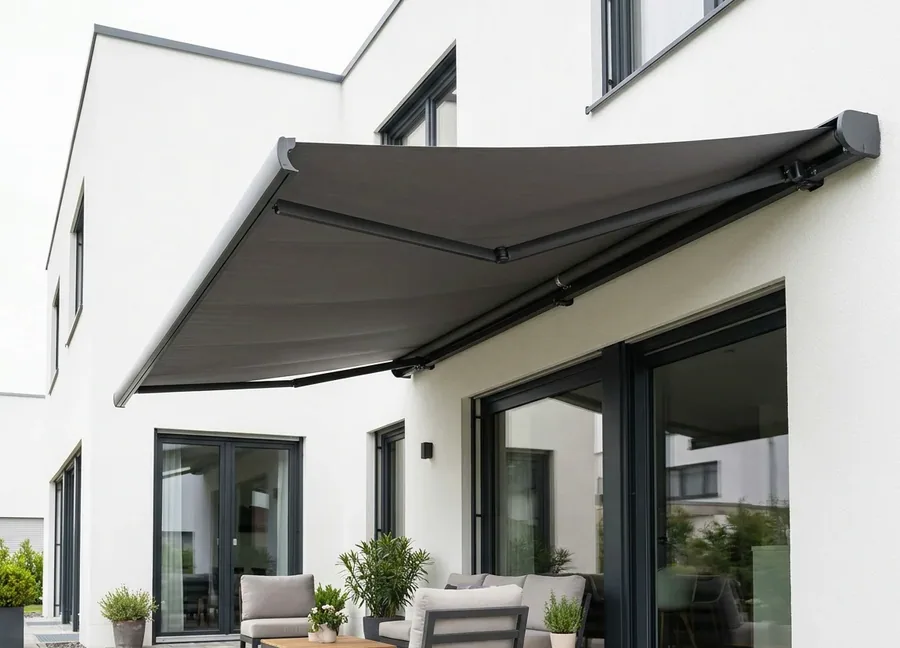 Folding-arm awning extended over a paved patio beside glazed doors